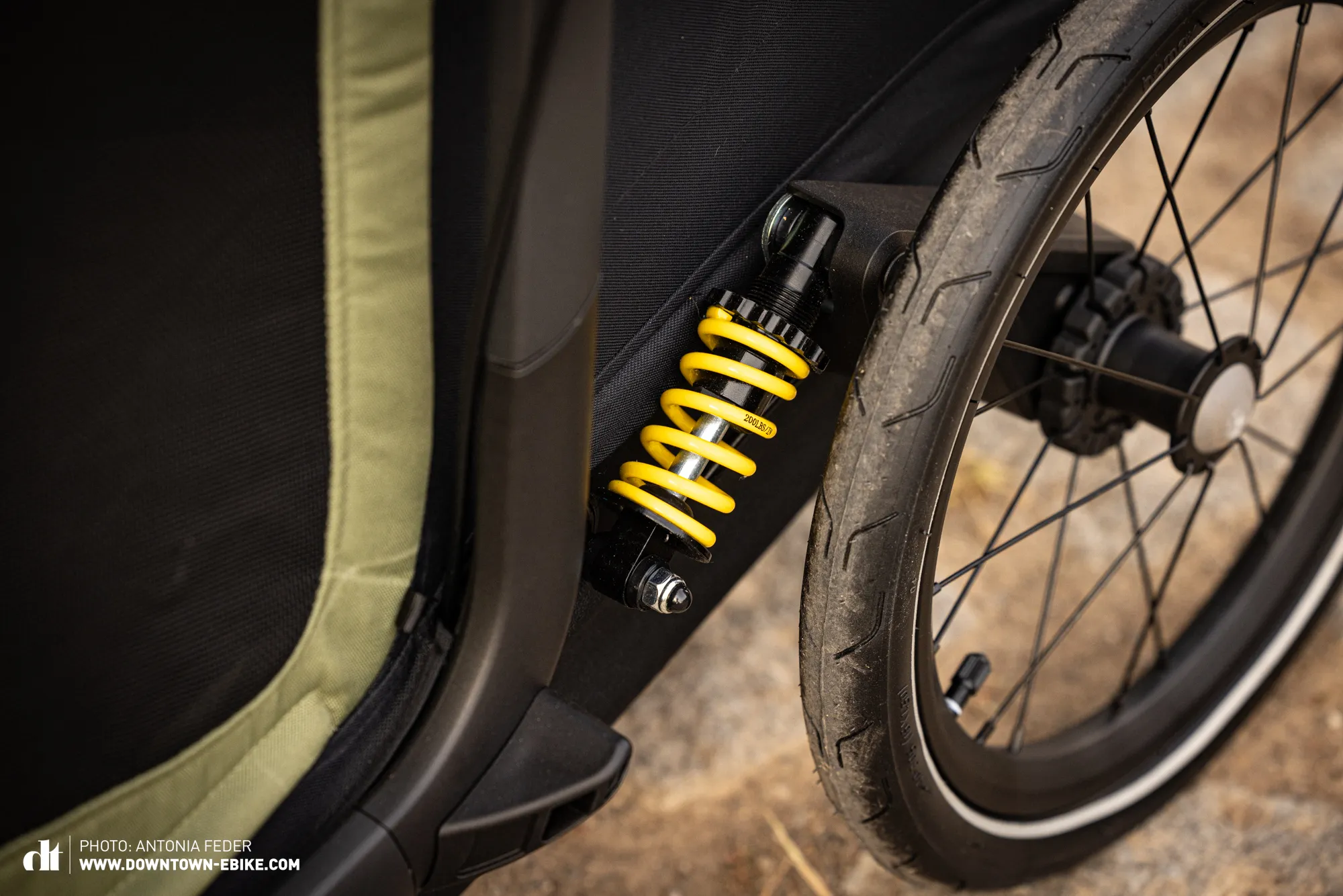 A bright yellow spring is prominently featured on the Hamax dog bike trailer's suspension.