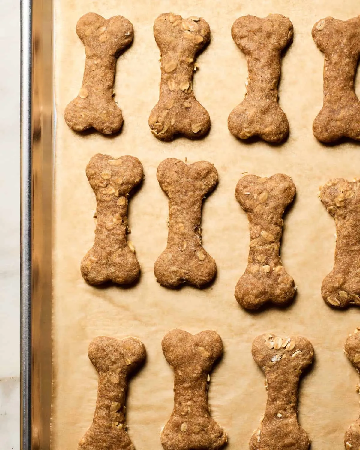 A close-up of baked homemade dog treats on a cookie sheet, ready to be cooled.