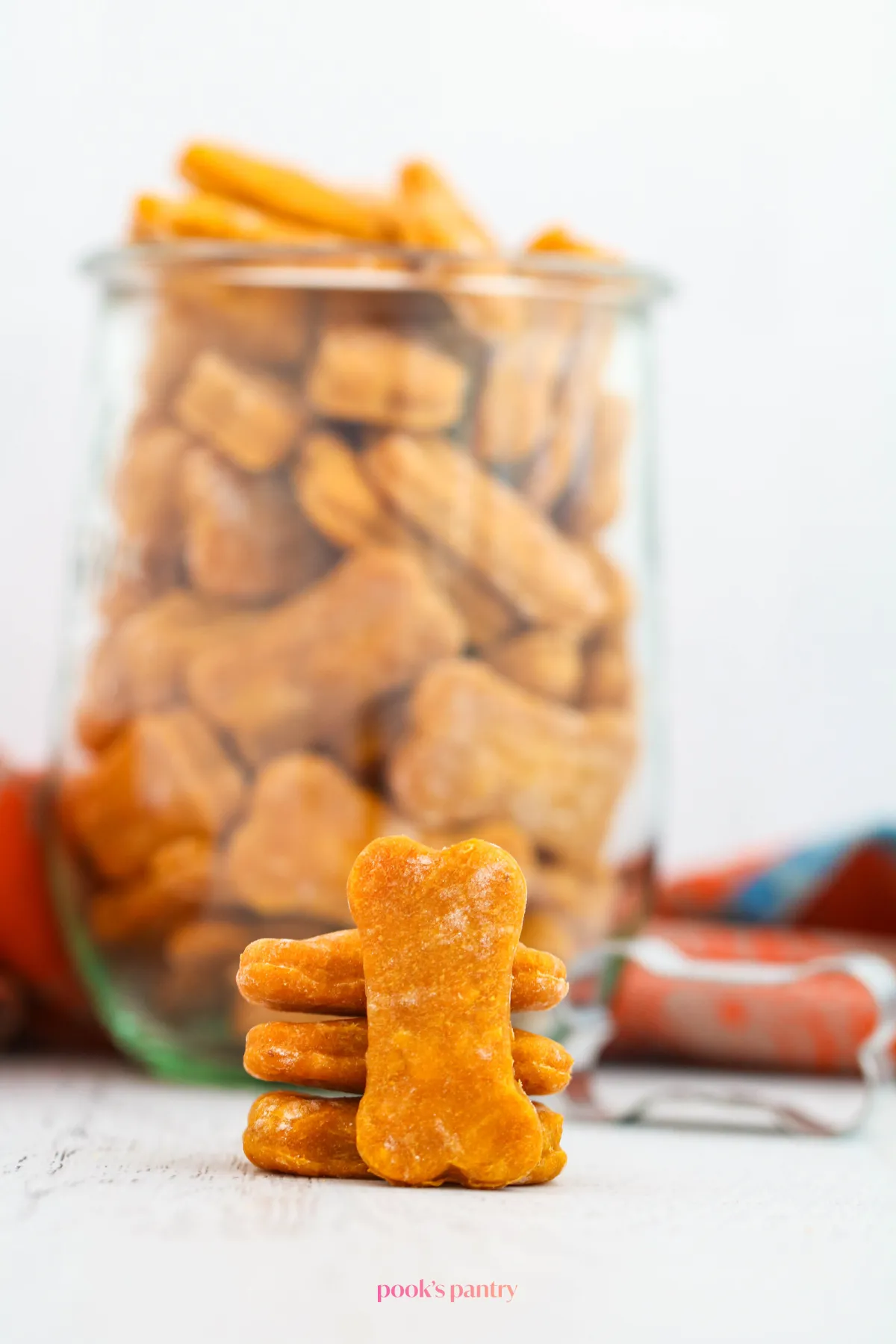 A collection of soft pumpkin treats suitable for older dogs, shown in a glass jar with a few stacked in front, ready to be enjoyed.