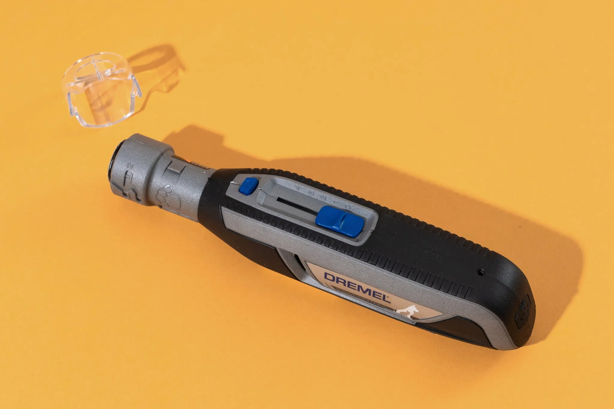 A Dremel PawControl dog nail grinder with its cap removed, resting on a bright yellow surface.