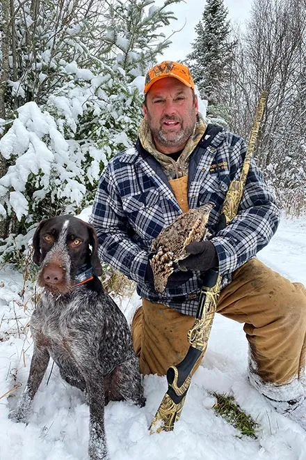 A German Wirehaired Pointer in a snowy wooded area