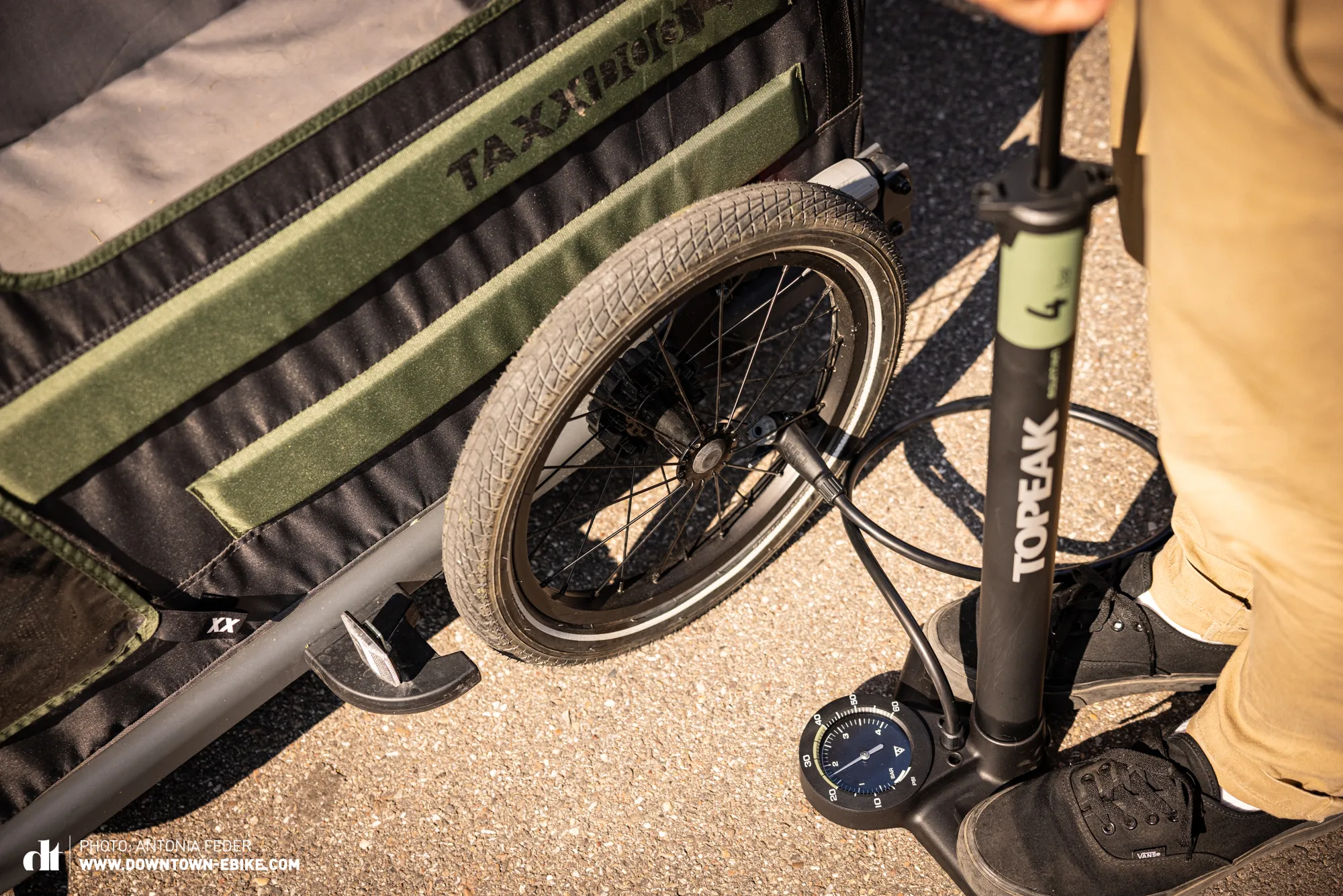 Before a ride, a person checks and inflates the tires of a dog bike trailer.