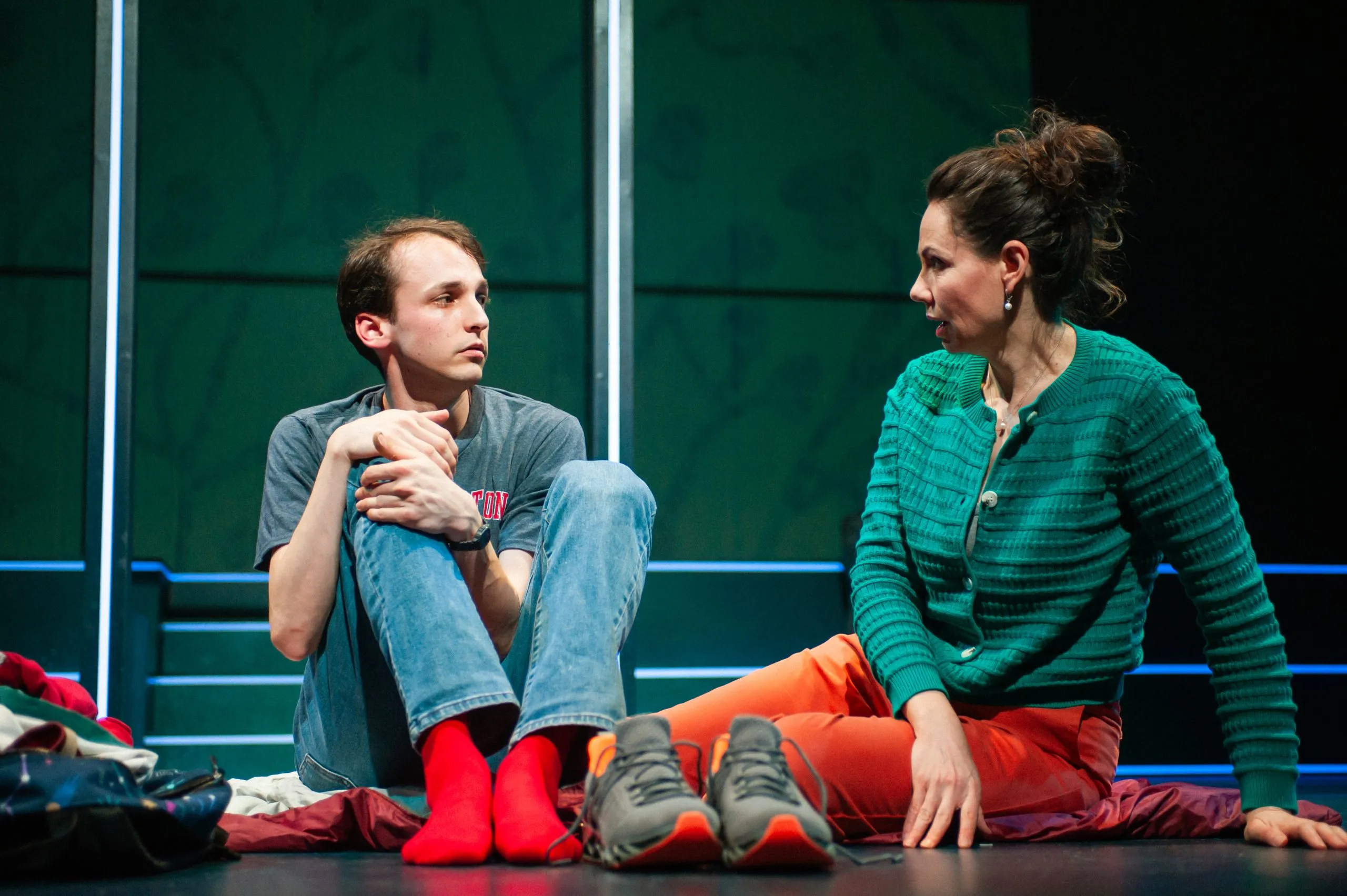 Christopher Boone, supported by his mother Judy, engages in a conversation with a police officer, highlighting family and legal challenges