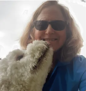 Deedra Thompson, a certified professional pet sitter, gently holding a puppy, symbolizing compassionate dog home sitting services.