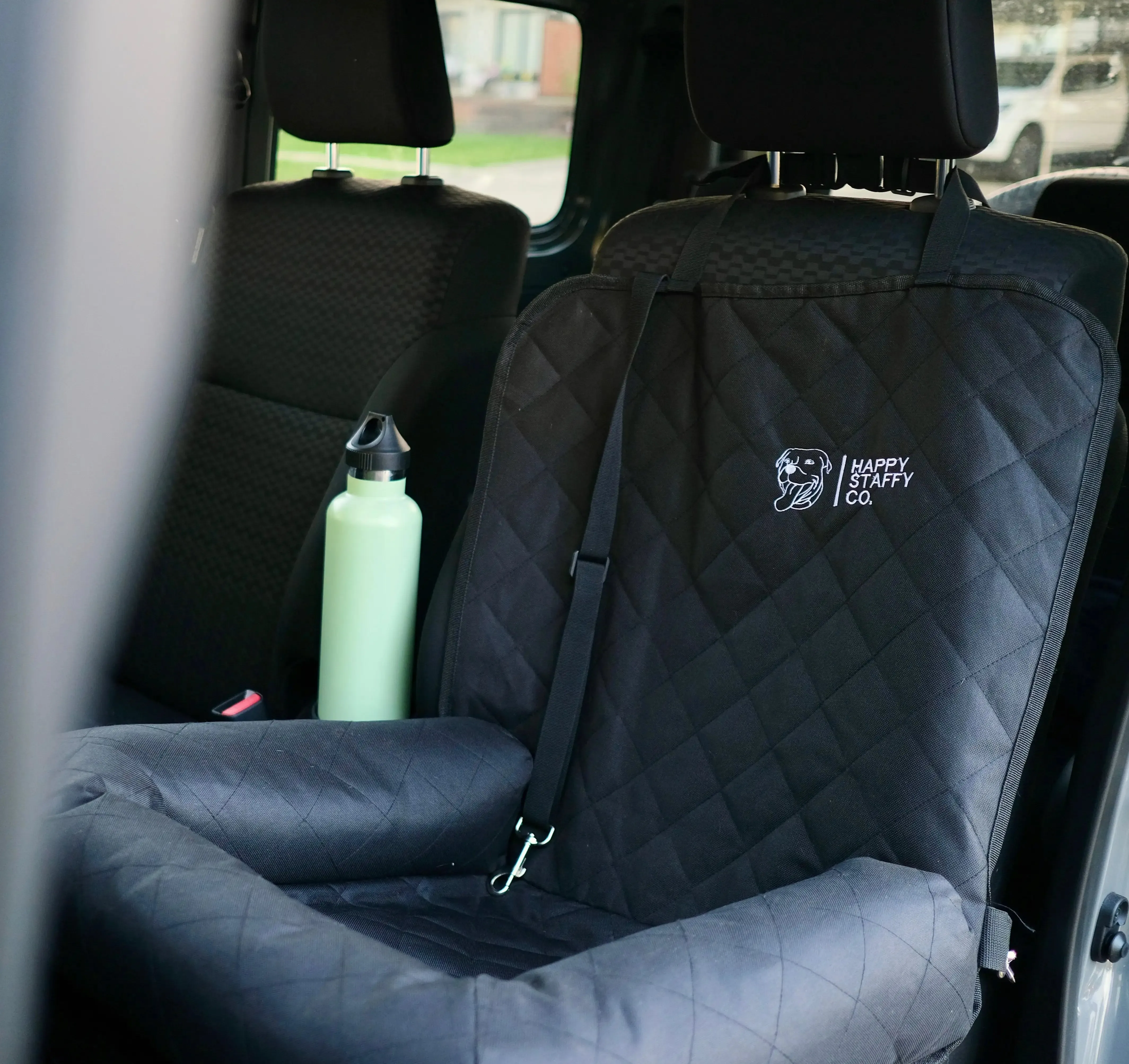 Dog secured with a dog seat belt on a single car seat protector, ensuring safe travel