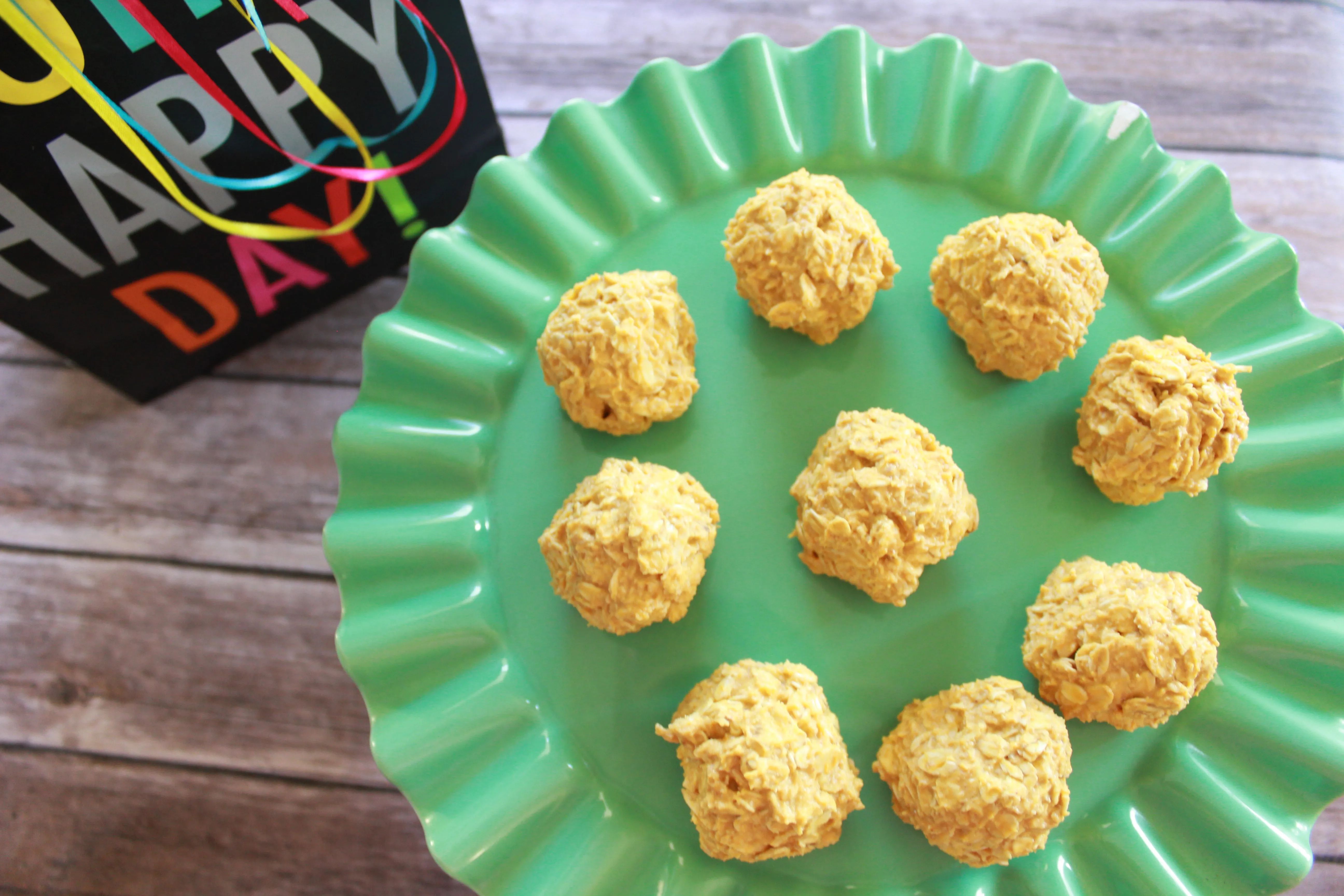 Hands mixing pumpkin puree, applesauce, peanut butter, and yogurt in a bowl, demonstrating the first step in making homemade soft dog treats no bake.