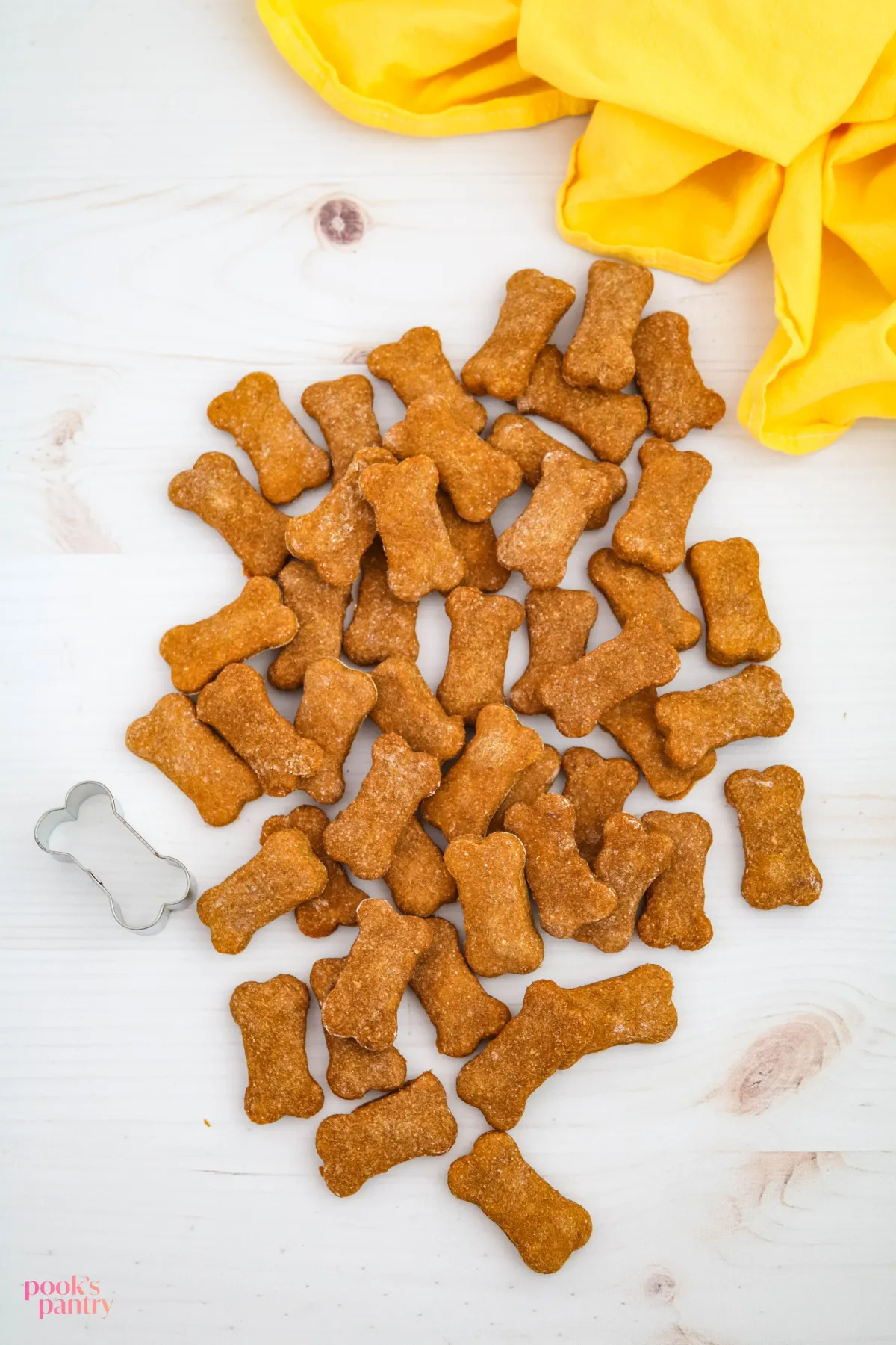 Homemade healthy pumpkin and banana dog treats cooling on a white background with a yellow towel, ready for pups.