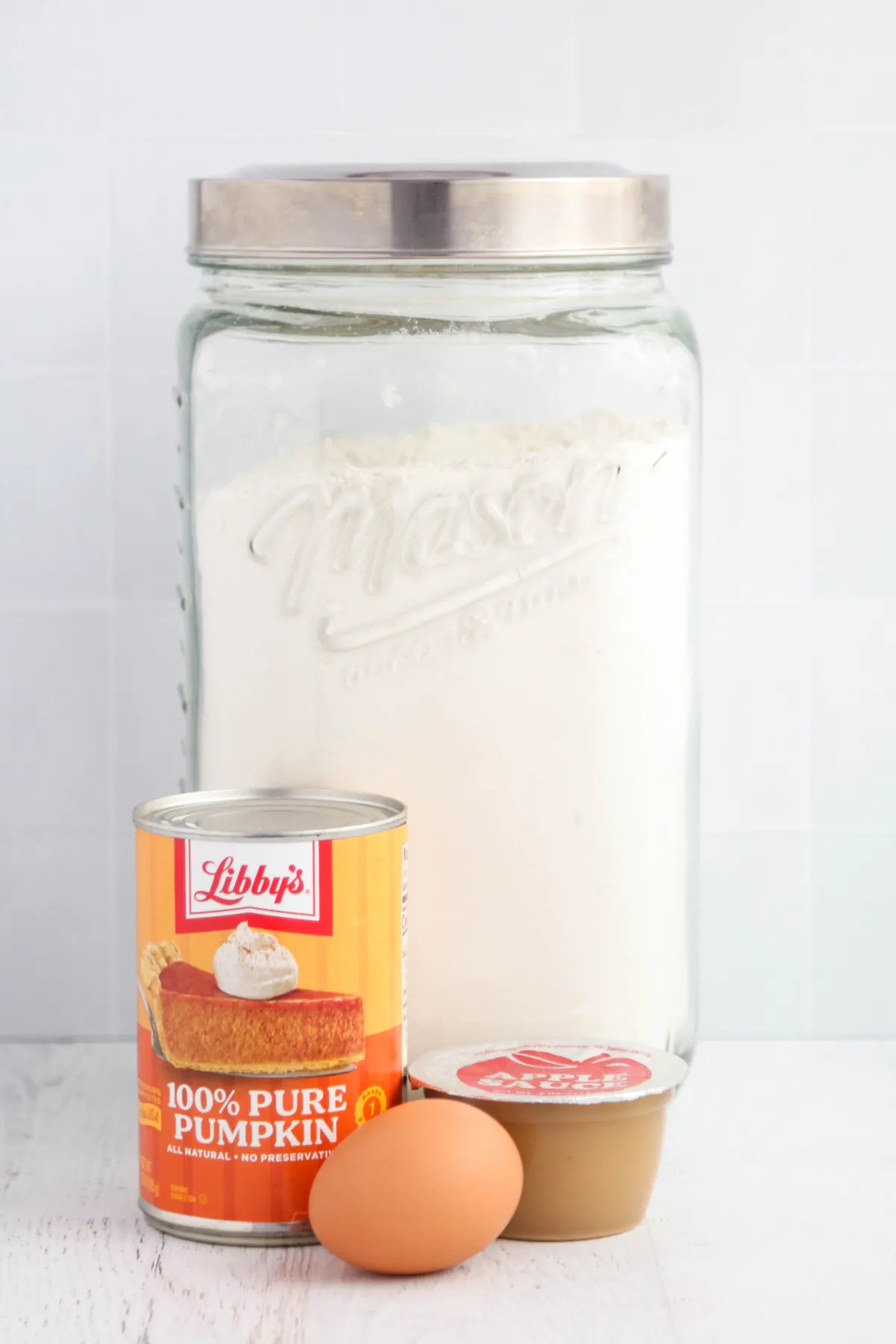 Ingredients for homemade soft dog treats: pumpkin puree, applesauce, egg, and flour.
