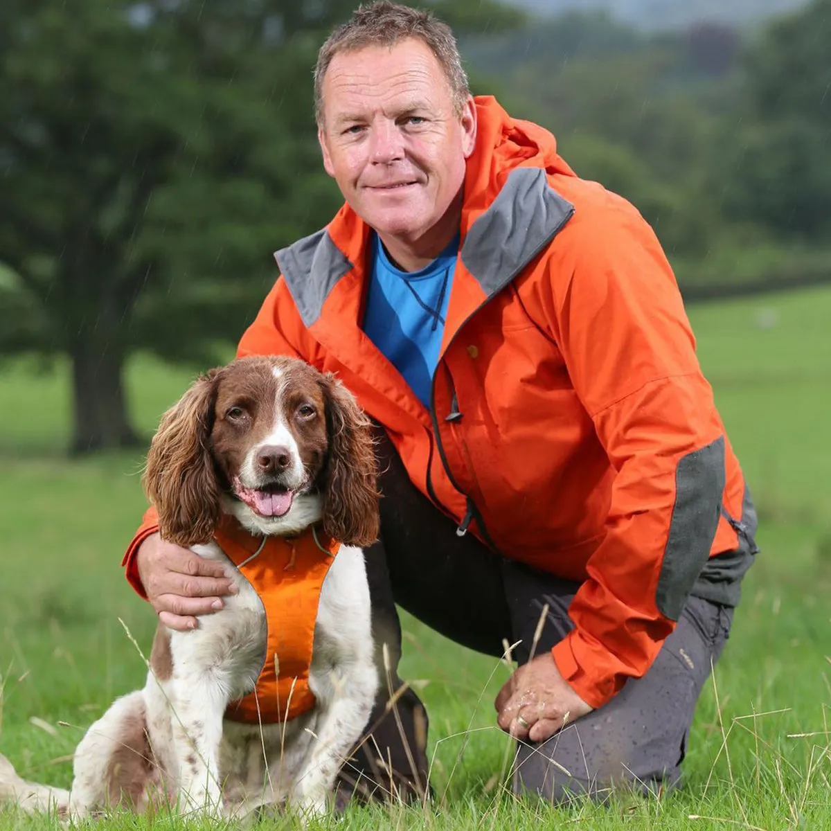 Kerry and his dog Max in an orange front harness on a scenic trail.