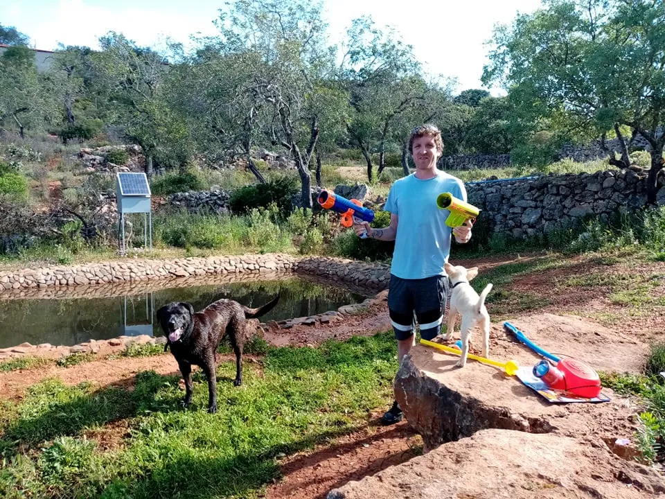 Lee smiling, holding a ball thrower, ready to play with a dog