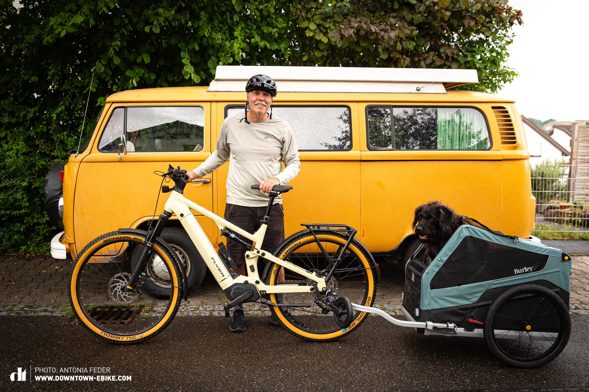 Manne stands beside his bicycle and dog trailer, which together form a long vehicle, similar to a VW bus.