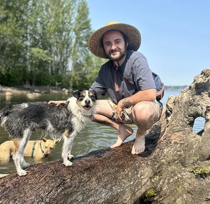 Max Rose of Mr. Pups Pet Care smiling while surrounded by a joyful pack of dogs at a Seattle dog park, showcasing strong bonds with his canine clients