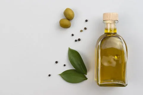 Olive oil bottle with leaves and olives on a table