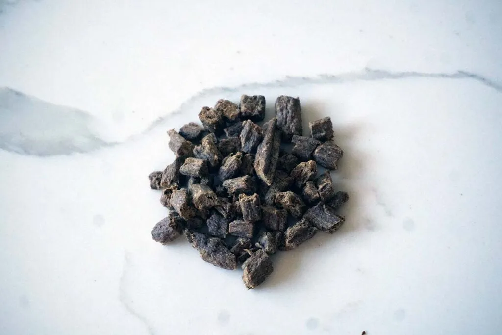 Pieces of Badlands Ranch dog food held by hand, illustrating its ready-to-serve format