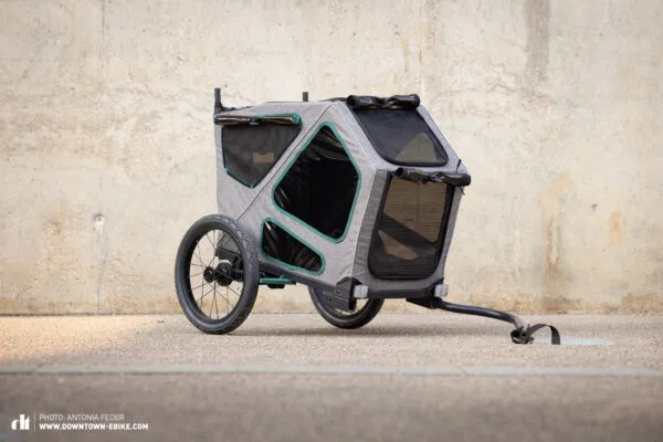 The TRIXIE Small Dog Trailer is featured against a natural backdrop.