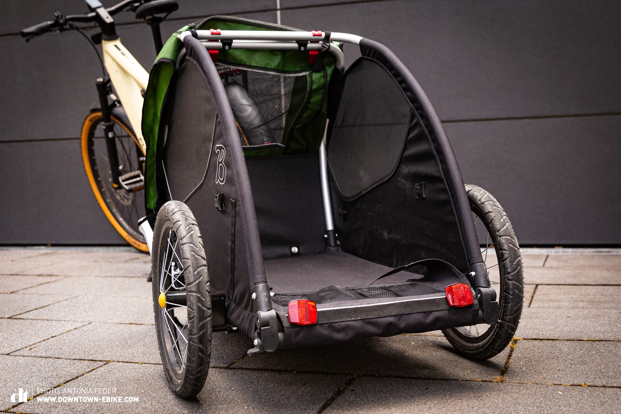 The unpadded interior of a bicycle dog trailer is shown, highlighting a hard, uncomfortable surface.