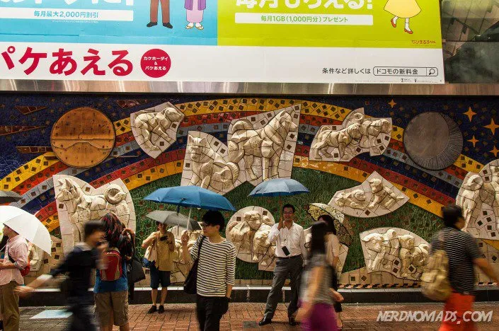 Vibrant mosaic artwork titled &quot;Hachiko Family&quot; depicting Hachiko playing with his kin on a wall at Shibuya Station