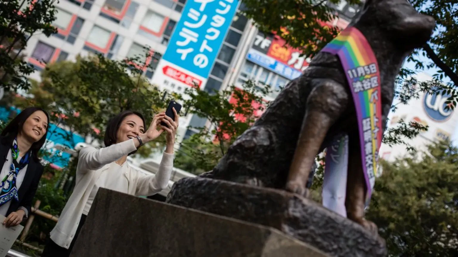 Visitors pose for a photograph next to the iconic Hachiko statue, a symbol of loyalty and a popular meeting spot.
