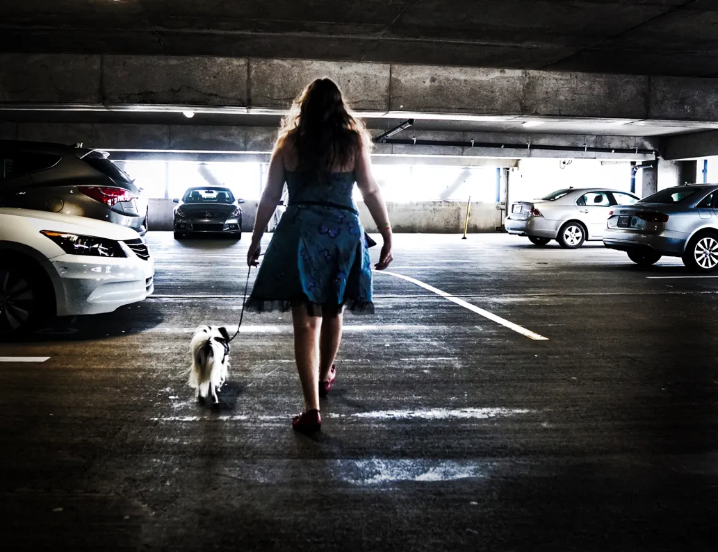 Woman and her service dog for anxiety walking through a parking garage