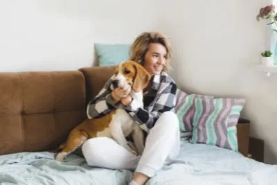 Woman snuggling a happy dog on a bed