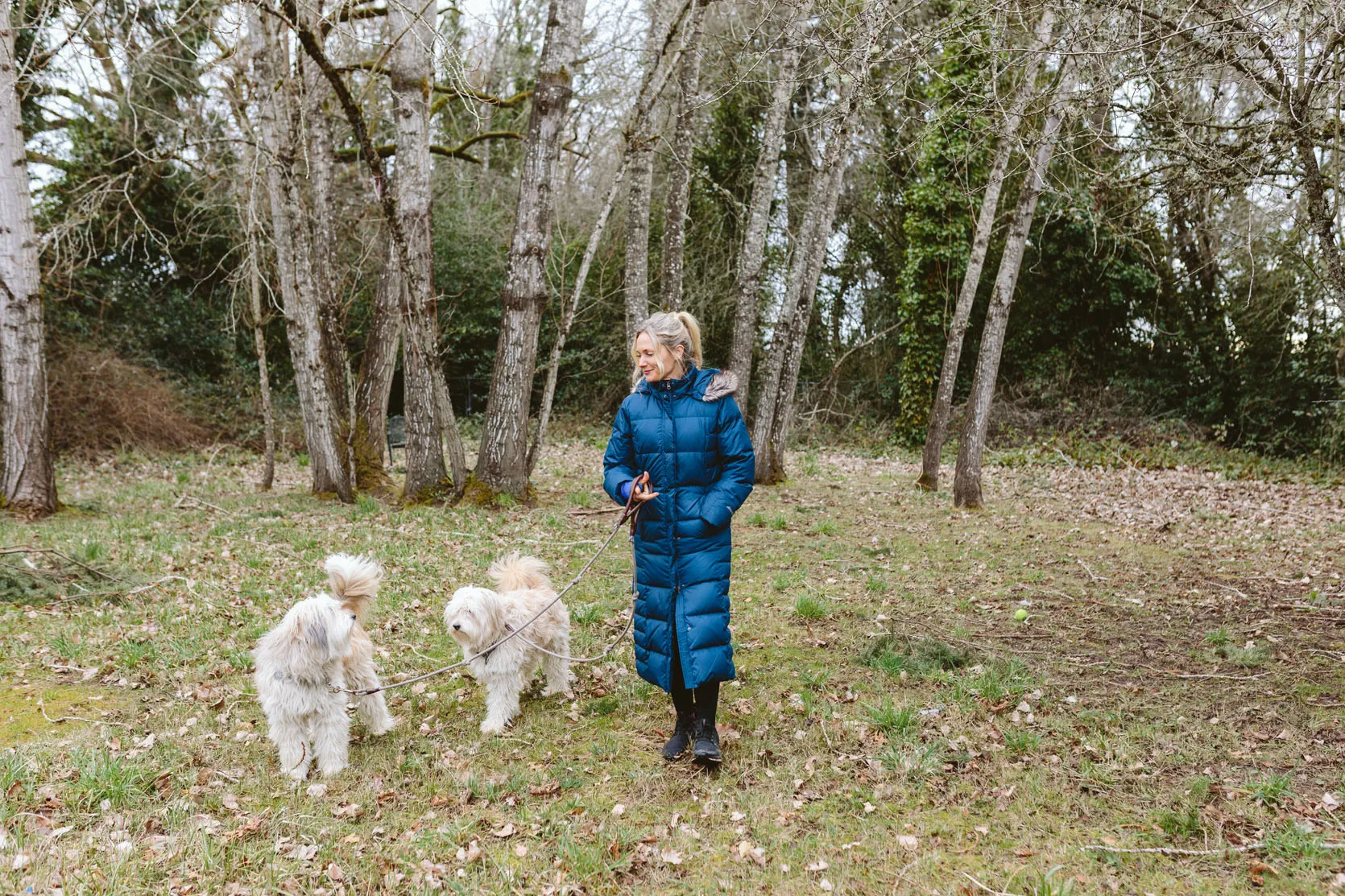 Woman wearing a long, warm winter coat designed for cold weather dog walks.