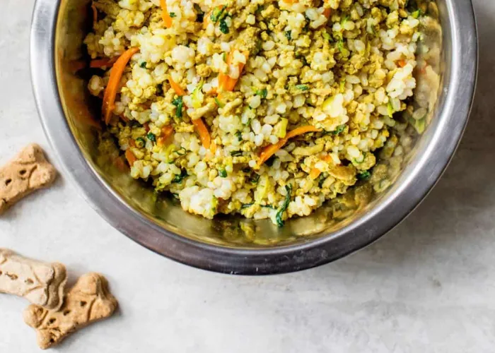 A casserole dish filled with shredded chicken, white rice, broccoli, and grated carrots