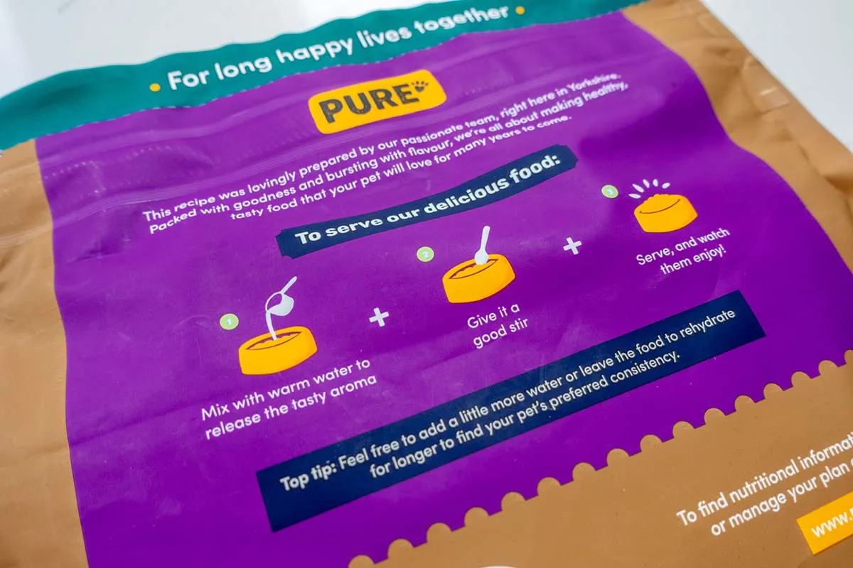 A dog happily looking at a bowl of Pure Pet Food, ready to eat.