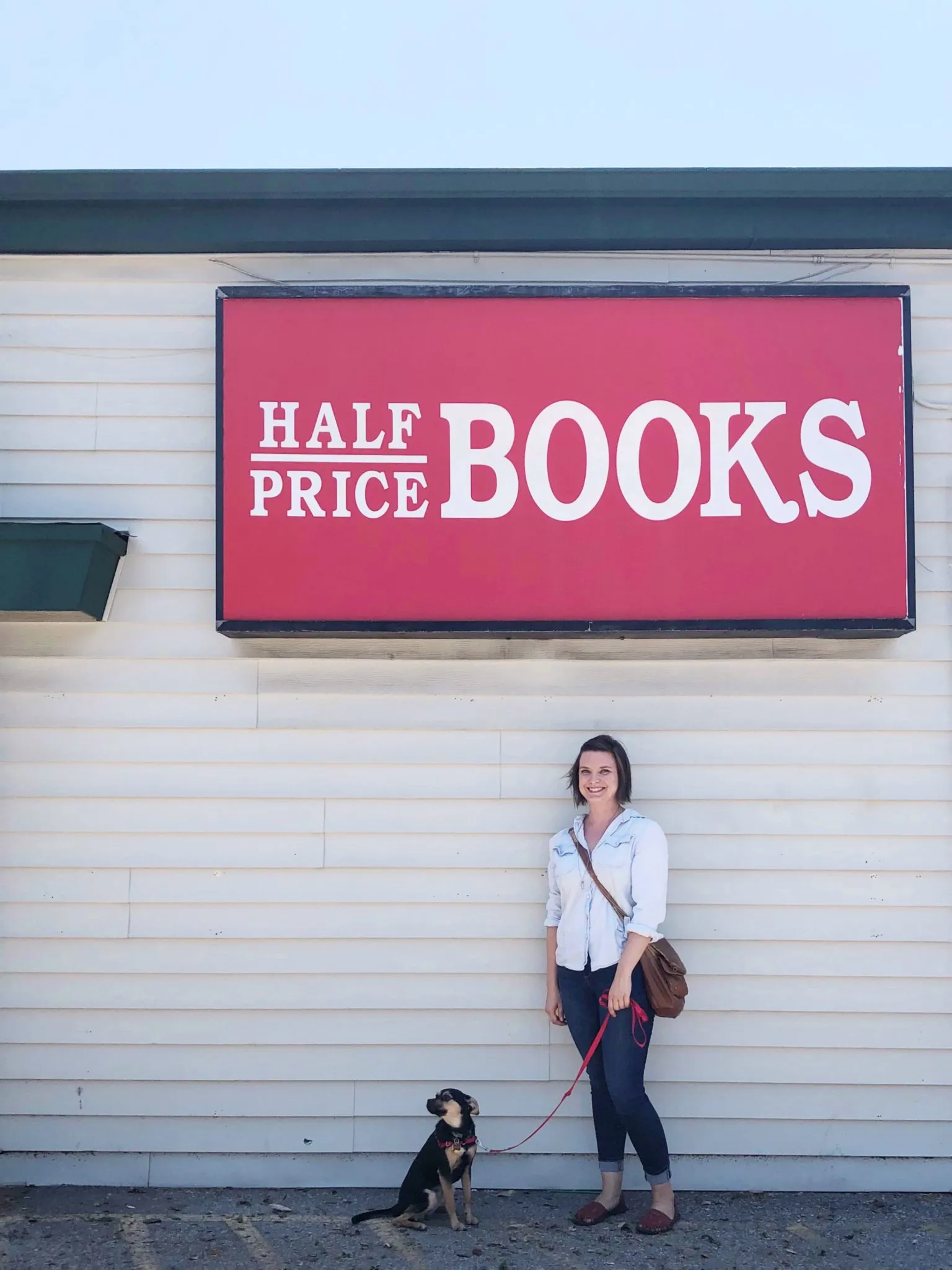 A dog sitting calmly next to a bookshelf at Half Price Books, demonstrating good public behavior