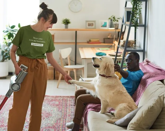 A dog walker cleaning up after a dog in a client's home, showing responsibility and care.