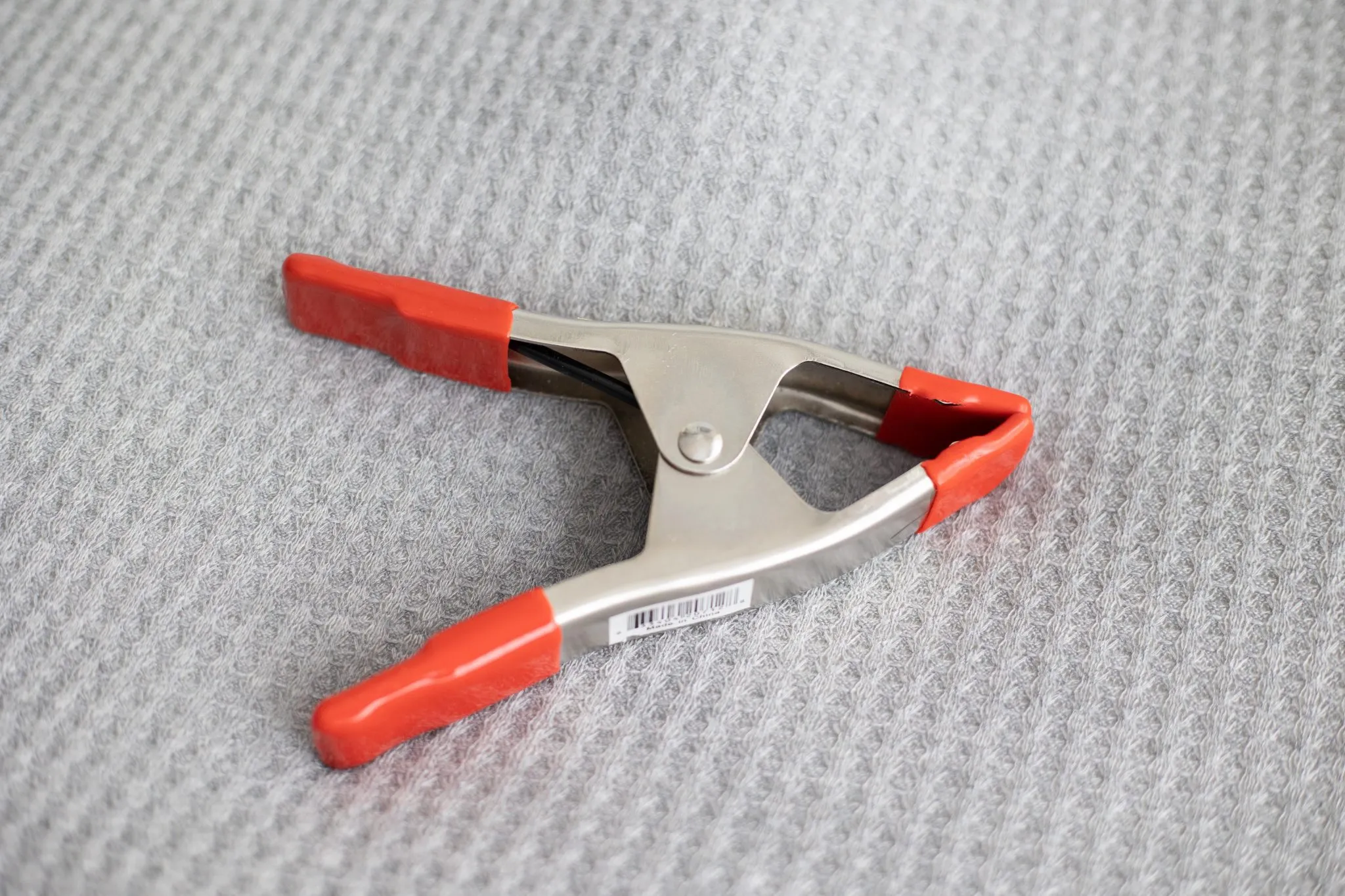 A durable metal clamp securing the fabric of an elevated dog bed, ensuring a taut surface.