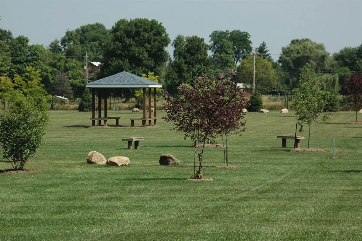A happy dog running through a lush, green, fenced-in bark park