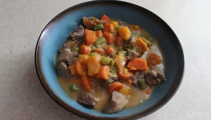 A hearty beef stew with chunks of meat, pumpkin, brown rice, and spinach in a bowl