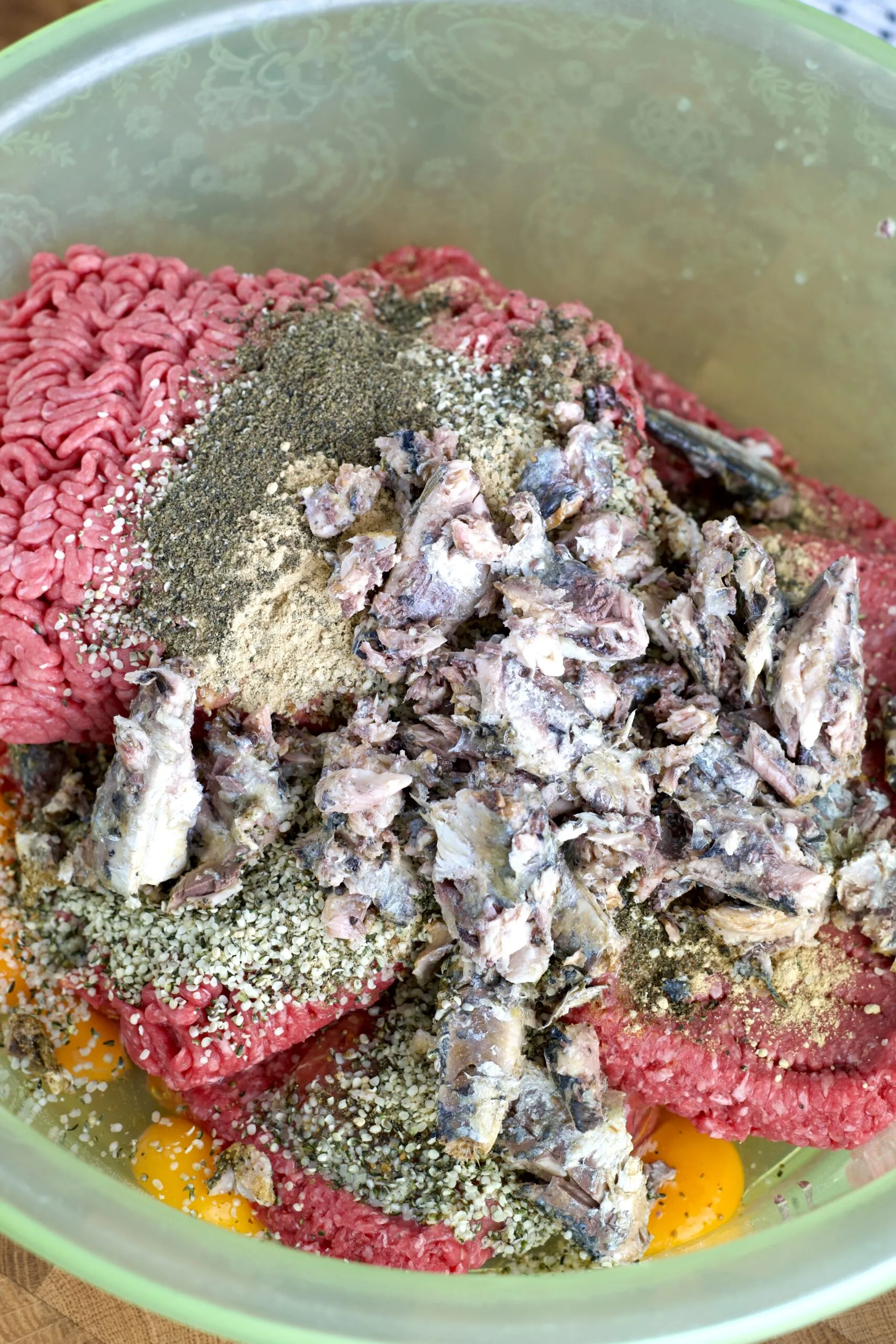 A large bowl filled with mixed ingredients, including ground meat, vegetables, and other supplements, ready for the next step
