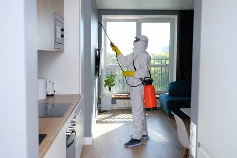 A person in a protective suit treating a room with disinfectant