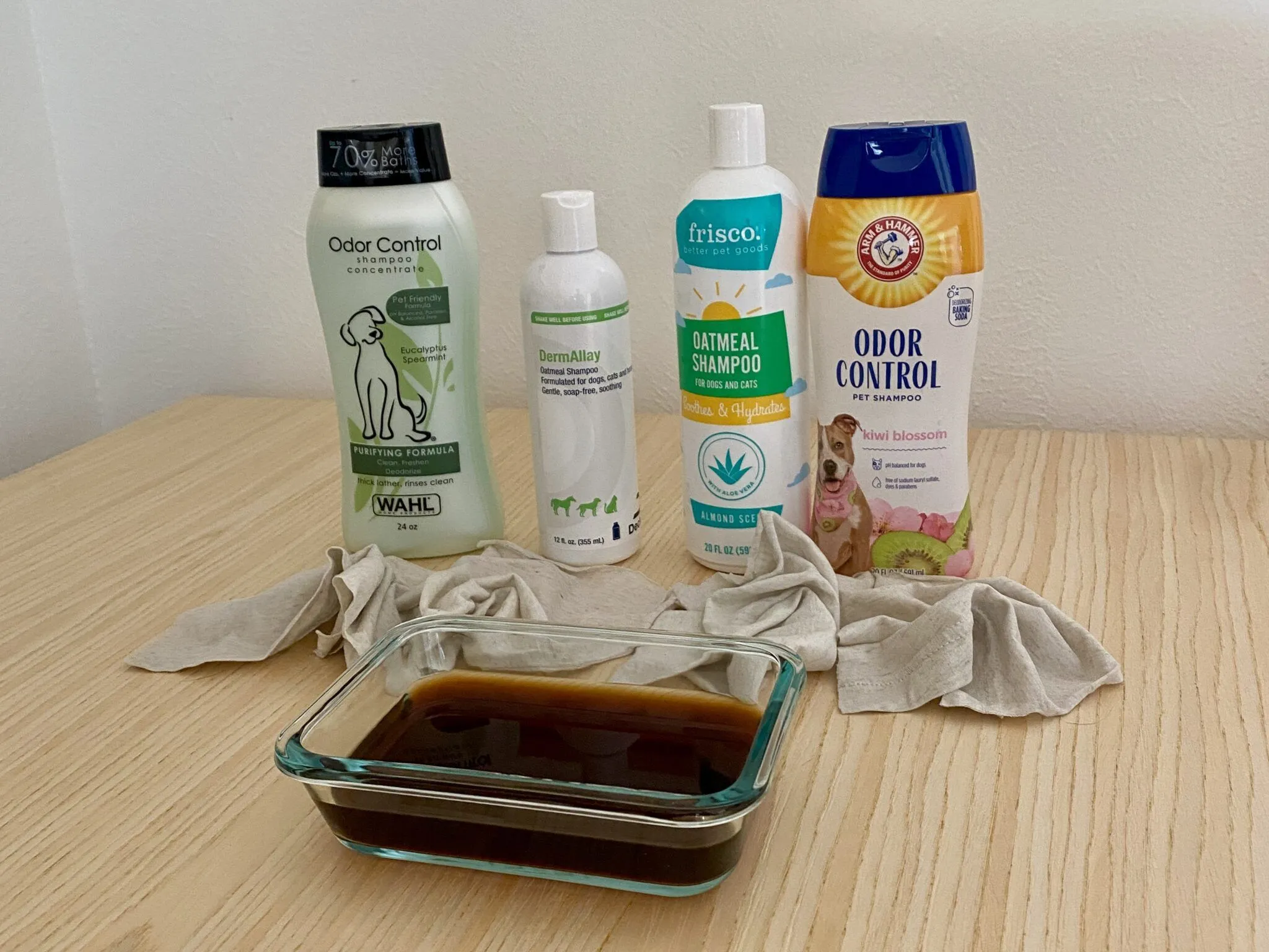 A person's hand washing a coffee-soaked rag with dog shampoo in a sink.