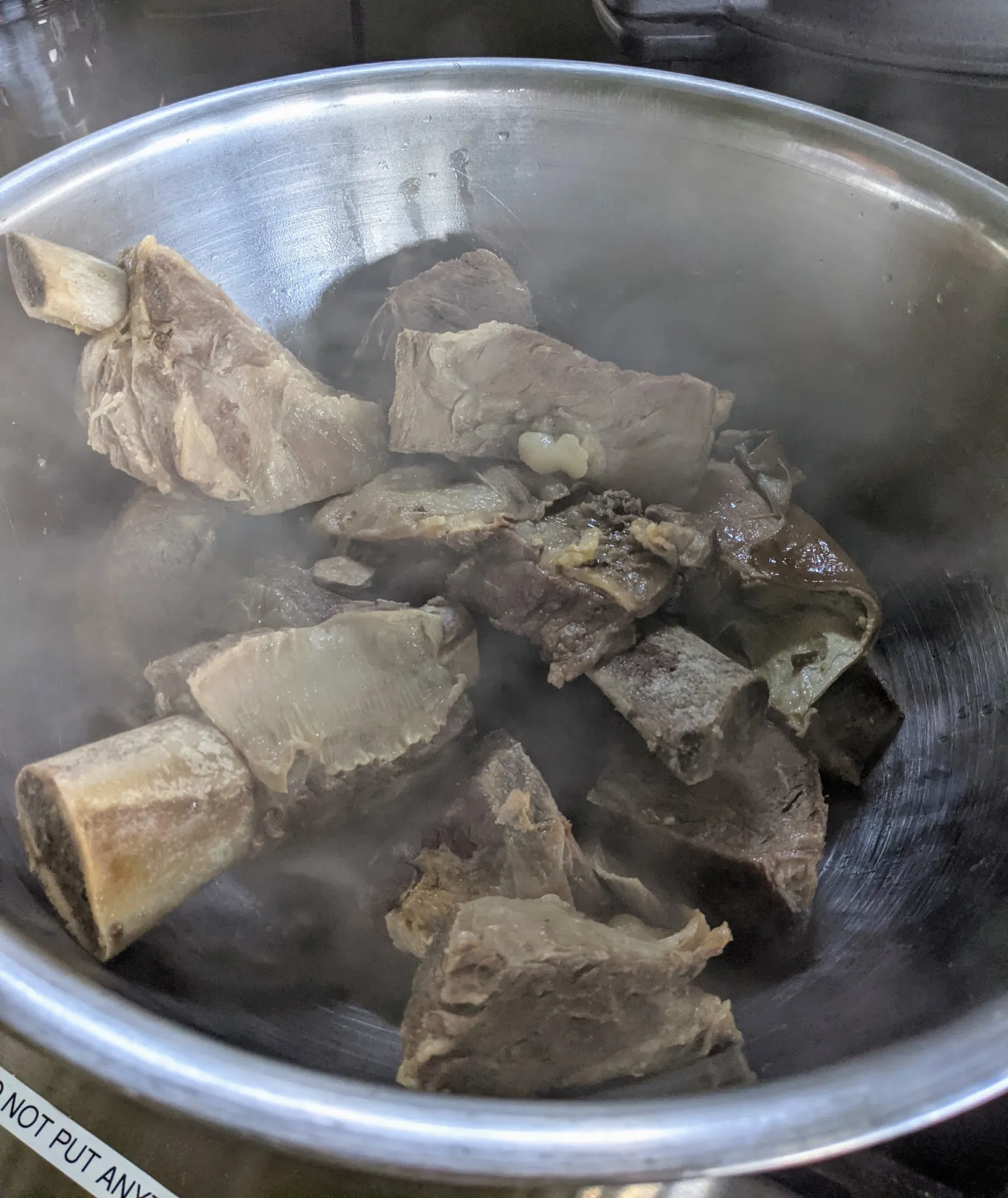 A pot of beef cooking, to be deboned and chopped after cooling for safe consumption.