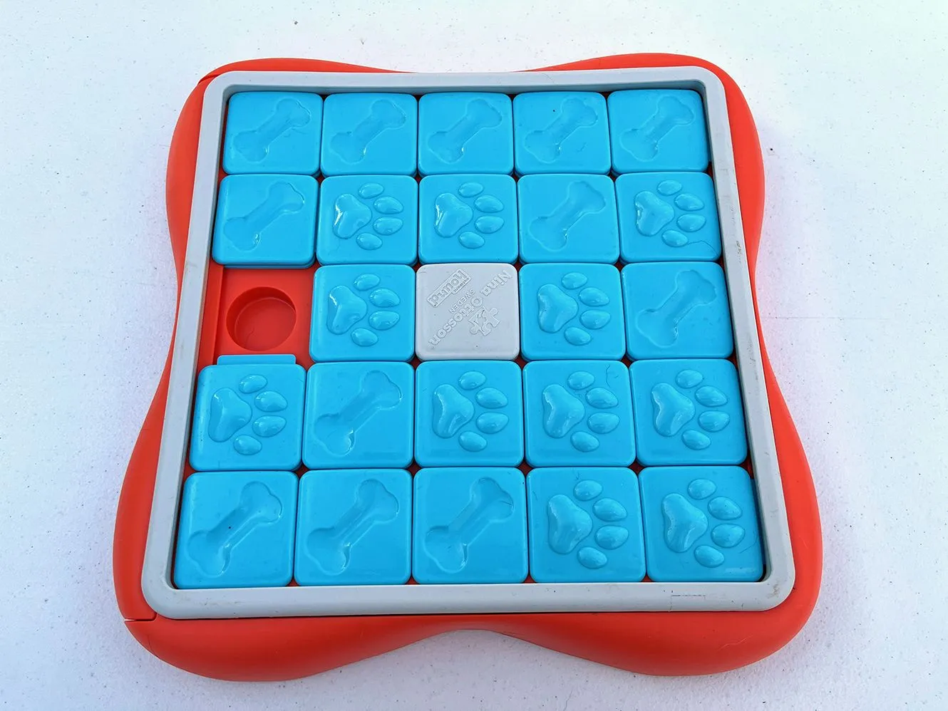 A sliding dog puzzle toy is displayed against a plain background.