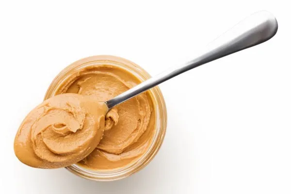 A spoon with creamy peanut butter, ready to conceal a dog's medication