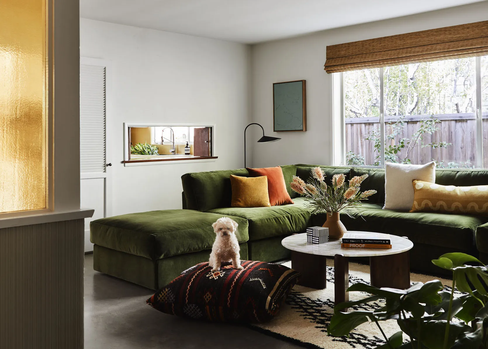 A stylish white and natural woven dog bed placed in a modern living room setting.