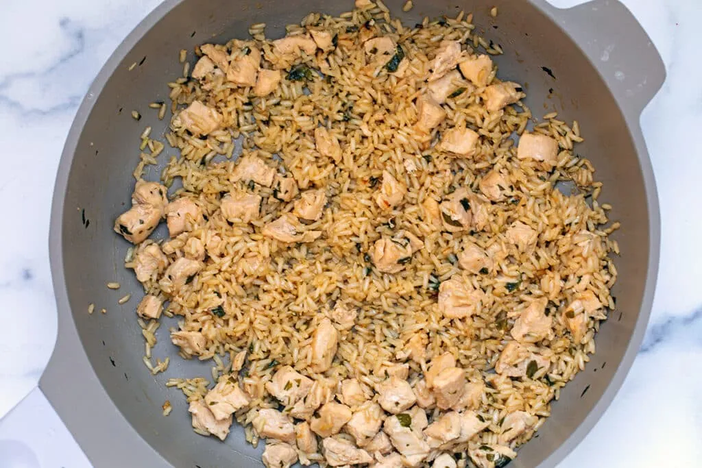Chicken, rice, and broth simmering together in a large skillet, forming a delicious meal for dogs.