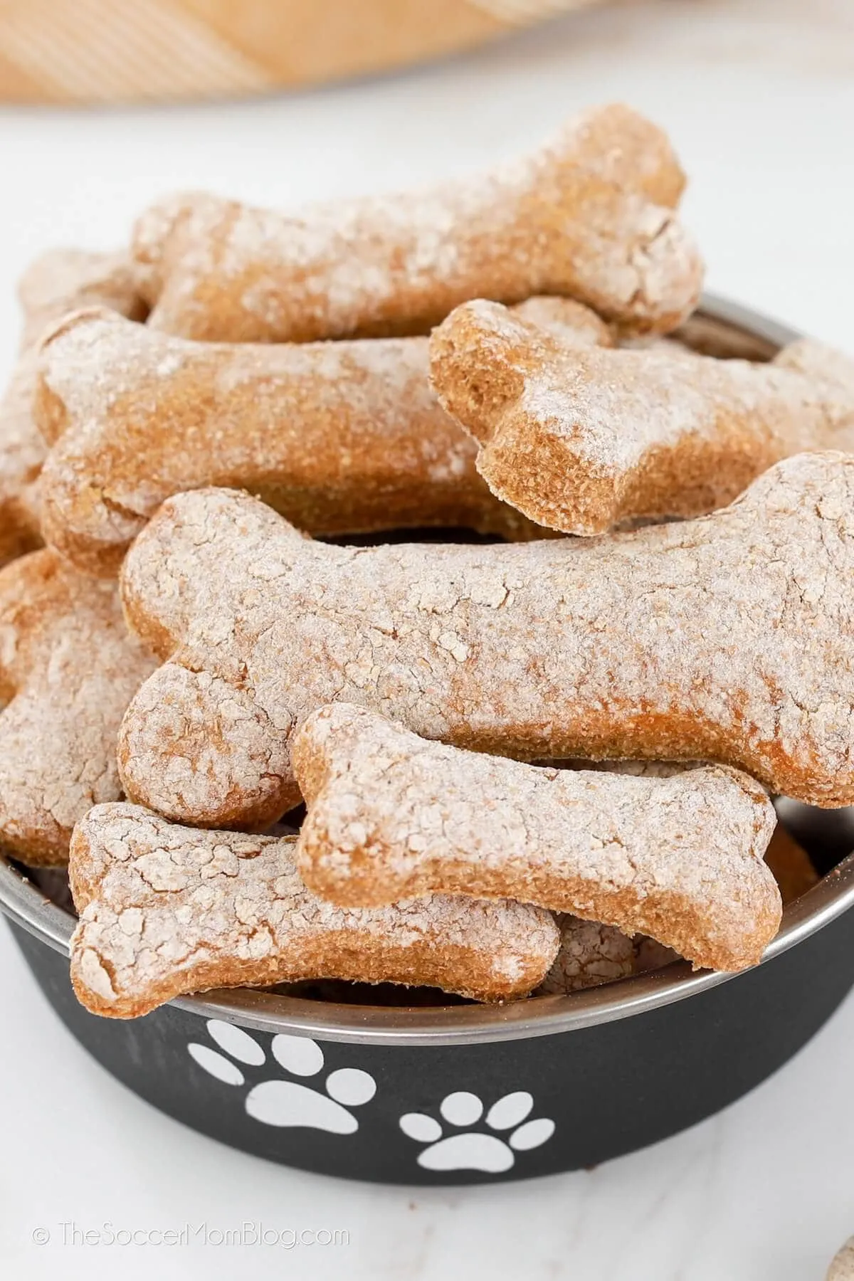 Close up of a bowl of bone-shaped dog biscuits, ready to be enjoyed by a happy dog.
