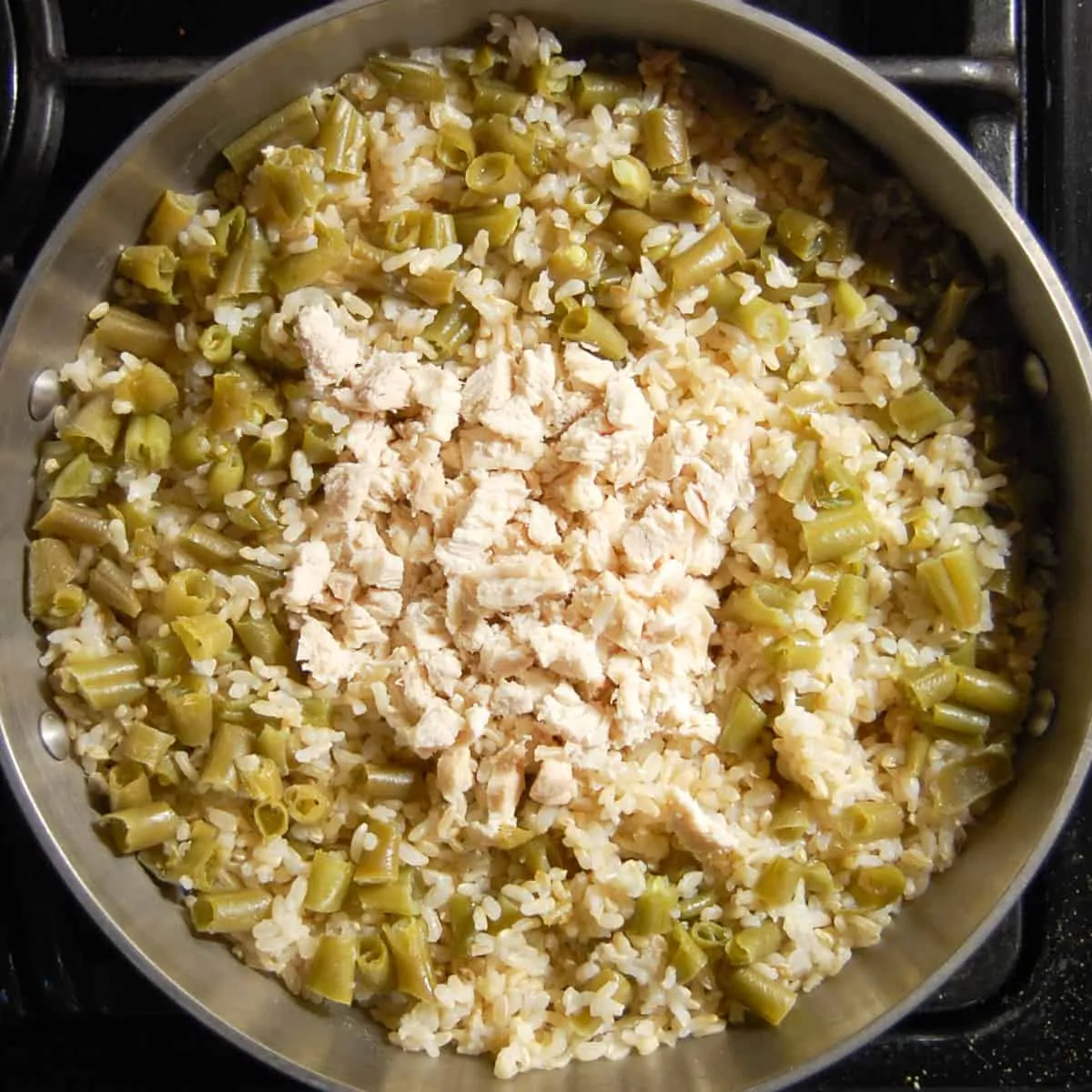 Cooked chicken and rice mixture with chopped green beans and shredded chicken breast