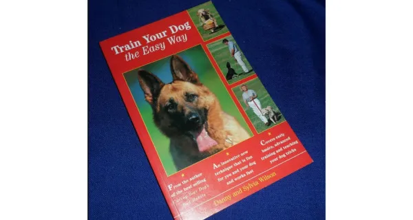 Cover of the "Train Your Dog the Easy Way" Bark Busters book, featuring two well-behaved dogs
