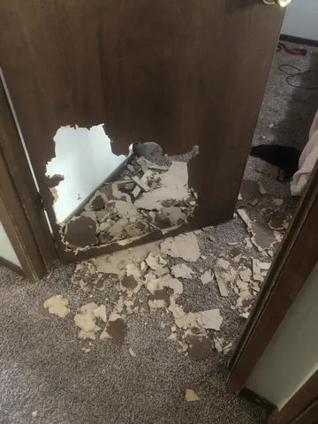 Dog damage including a chewed-through wooden door in a home after escaping a crate.