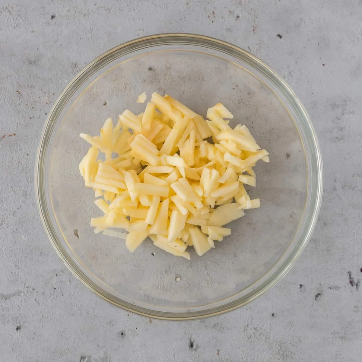 Finely chopped apple in a small glass bowl, ready to be combined with other ingredients