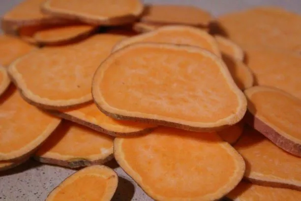 Fresh sweet potatoes on a wooden cutting board ready for slicing