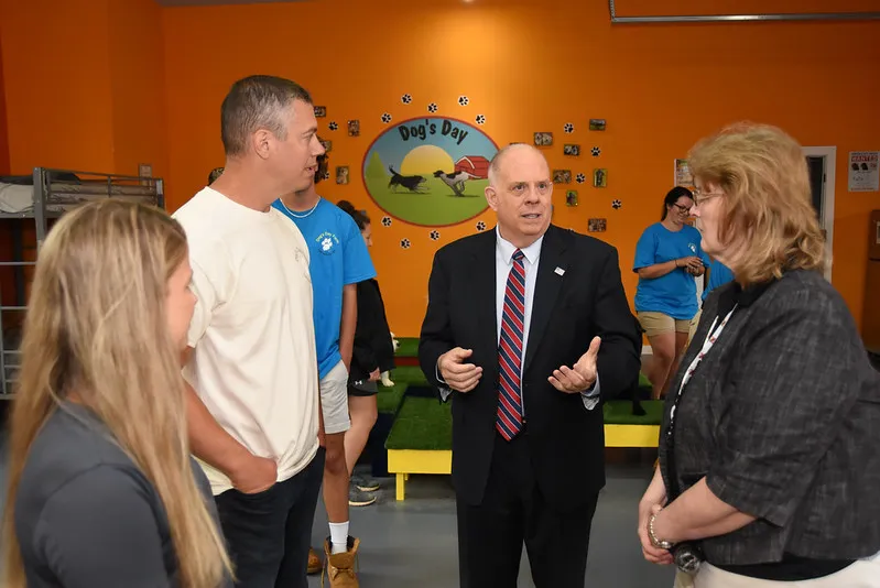 Governor Larry Hogan smiling and interacting with a dog during a visit to the farm