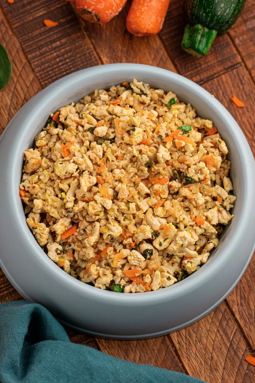 Portioned homemade turkey and rice dog food in a storage container, with fresh carrots and zucchini on the side, emphasizing vet-approved nutrition.