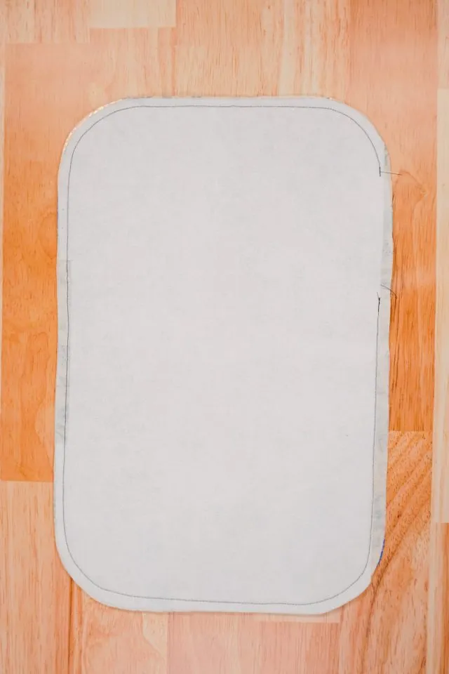 Sewing around the edge of the layered fabric with a sewing machine, leaving an opening