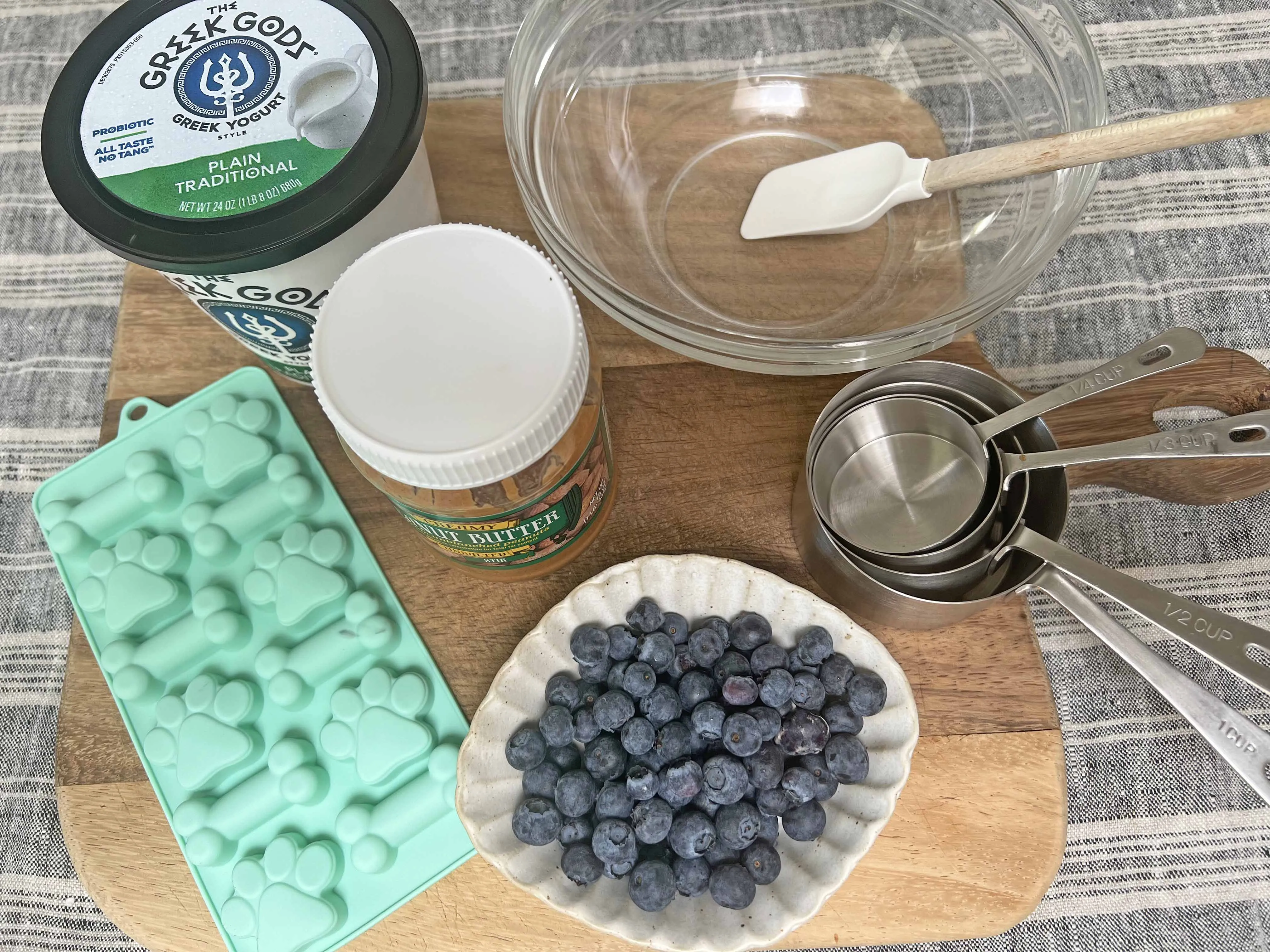 The simple, healthy ingredients laid out for homemade dog treats: plain Greek yogurt, natural peanut butter, and fresh blueberries